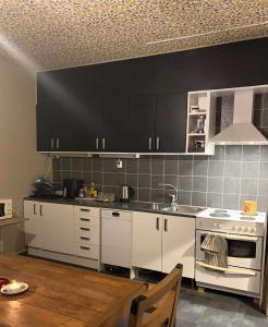 een keuken met witte kasten en een zwarte muur bij Helsingebockens Fastigheter 