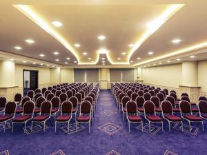 Una habitación con filas de sillas y un escenario en ella. en Mercure Tetovo, en Tetovo