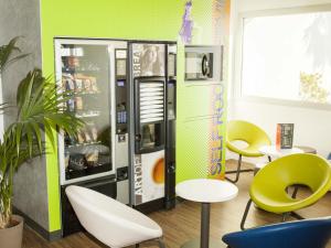 Una habitación con una máquina expendedora con sillas y mesas. en ibis budget Bordeaux Est Lormont, en Lormont
