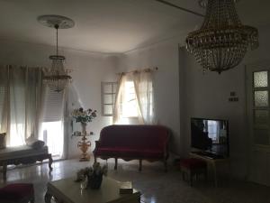 sala de estar con sofá, TV y lámparas de araña en Maison de Sila, en Bir el Djir