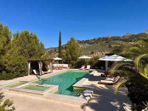 Hacienda el Tarajal في بييغو ذي كوردوبا: مسبح وكراسي ومظلات بجانب جبل