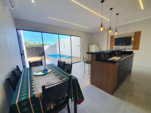 a kitchen and dining room with a table and a counter at Casa de Alto Padrão com 5 Suítes e Piscina in Foz do Iguaçu