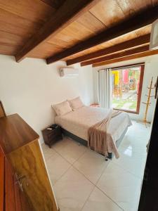 une chambre avec un lit et une grande fenêtre dans l'établissement Corumbau Chalé Casa, à Prado