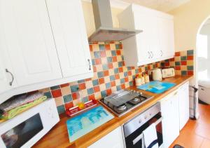 Una cocina con gabinetes blancos y un horno de estufa. en The Beach House! Just Steps from the Beach - Perfect for Couples & Family Stays with Private Parking, Large Garden & Fast Free WiFi - The Perfect Seaside Getaway to Sutton on Sea, en Sutton-on-Sea