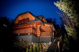 a wooden house is shown at night at Nebbia Ressort in Karpacz