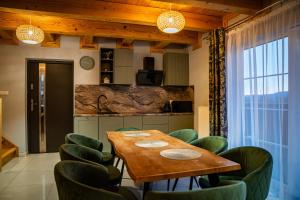 a dining room with a wooden table and green chairs at Nebbia Ressort in Karpacz