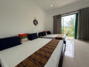 Aura Villa في بولوناروا: سريرين في غرفة بها نافذة