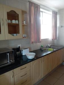 een keuken met een aanrecht met een magnetron en een wastafel bij Albatros 106 in Amanzimtoti +3 foto's