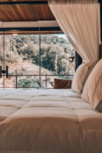 un grand lit dans une chambre avec une grande fenêtre dans l'établissement Cabana Terra Nossa com vista, à Marechal Floriano