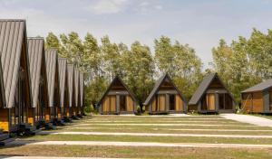a row of wooden cottages with trees in the background at Ranch in Variani in Variani