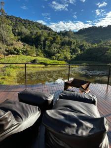 a deck with couches and a table and a river at Cabana Terra Nossa com vista in Marechal Floriano