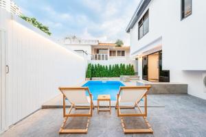 eine Terrasse mit zwei Stühlen und einem Swimmingpool in der Unterkunft SavasdeeVilla Midtown bangkok in Makkasan