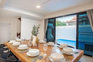 ein Holztisch mit Gläsern und Tellern darauf in der Unterkunft SavasdeeVilla Midtown bangkok in Makkasan