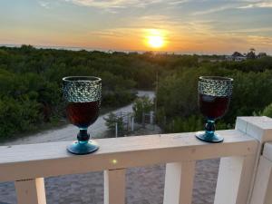 twee glazen wijn zittend op een leuning met de zonsondergang bij HOLBOX PUERTA DEL MAR in Holbox Island