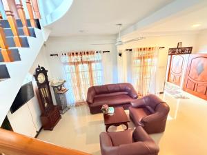 a living room with two couches and a clock at Pineapple Surf Villa in Ahangama