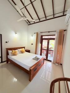 a bedroom with a bed and a large window at Pineapple Surf Villa in Ahangama
