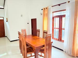a dining room with a wooden table and chairs at Pineapple Surf Villa in Ahangama