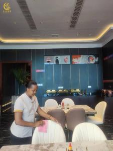 een vrouw die naast een tafel staat in een restaurant bij Lan Ting massage hotel in Dar es Salaam +21 foto's
