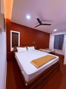 a bedroom with a large bed with a ceiling fan at Western Castle Stay n lawn in Coimbatore