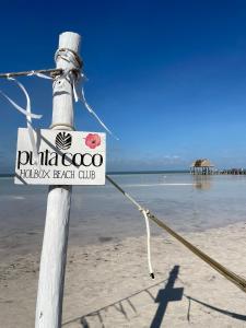 een bord op een paal op het strand bij HOLBOX PUERTA DEL MAR in Holbox Island