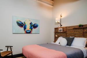 ein Schlafzimmer mit einem Bett und einem Kuhgemälde in der Unterkunft Penthouse City Overlook 2BR Apartment - free parking in Appleton