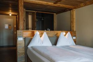 a large bed with white pillows on top of it at Alpenblick Weggis - Panorama & Alpen Chic Hotel in Weggis