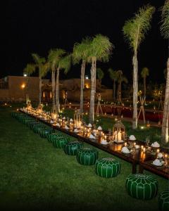 a long table with candles and palm trees at night at Al destino Resort Marrakech in Marrakech