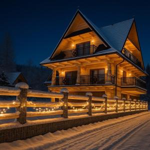 a house with lights on the side of it at night at Villa Alexandra jacuzzi i sauna in Kościelisko