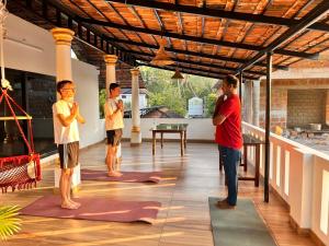 Un grupo de tres hombres de pie sobre colchonetas de yoga en una casa. en Marari Beach Cleetus Homestay, en Alleppey