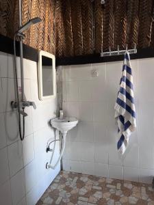 ein Bad mit einem Waschbecken, einem Spiegel und einem Handtuch in der Unterkunft Kibwana Beach Bungalows & Diving in Matemwe