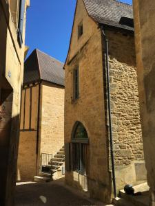 - un vieux bâtiment en pierre avec une arche dans une rue dans l'établissement Maison de Charme dans la Cité, à Sarlat-la-Canéda