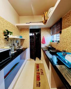 バンガロールにあるEden Green Nestの黒いカウンタートップと青いシンクのあるキッチン