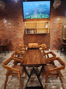 a wooden table with chairs and a tv on a brick wall at Mi Amor Luxury Hostel located in South Island Center in Phu Quoc