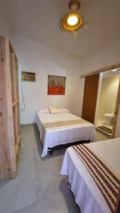 una camera d'albergo con due letti e uno specchio di Pura Vida Hostel e Pousada - Boipeba a Ilha de Boipeba