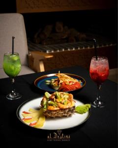 two plates of food on a table with two drinks at Al destino Resort Marrakech in Marrakech