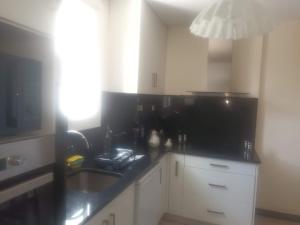 een keuken met witte kasten en een zwart aanrechtblad bij Super Apt terrasse 2box in Olivet