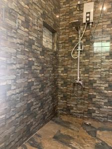 a bathroom with a stone wall with a shower at Menuks villa in Habaraduwa Central