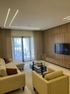 a living room with couches and a flat screen tv at Hawana Apartment in Salalah