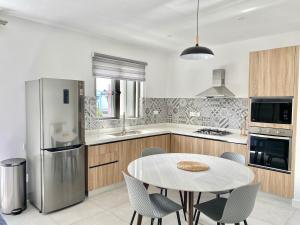 a kitchen with a table and a refrigerator at Tempus Central - Bazaar Metro Supermarket Resto in Quatre Bornes