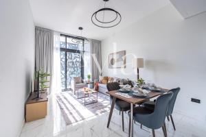 a white living room with a table and chairs at The Gate Executive 2BR on Masdar City by Ayla in Abu Dhabi Intl