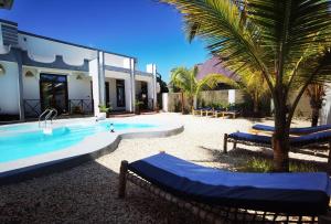 una piscina con due sedie a sdraio e una casa di Villa Flower Zanzibar a Kiwengwa