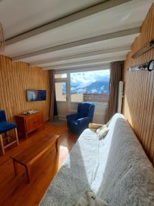 a bedroom with a bed and a chair and a window at Logement 48m2- 2 chambres in Orcières