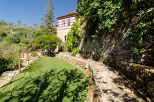 a house with a green lawn in front of a wall at Chalet Monchique in Monchique