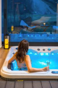 a woman in a hot tub with a glass of wine at Valdora Forest Oasis - Spa Villa Fužine in Fužine