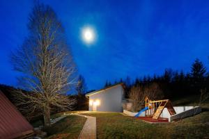 una vista notturna di una casa con la luna nel cielo di Valdora - Forest Oasis 