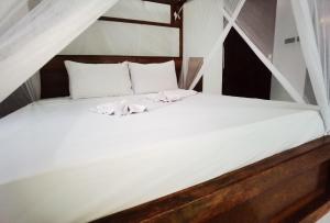un letto bianco con due asciugamani bianchi di Villa Flower Zanzibar a Kiwengwa