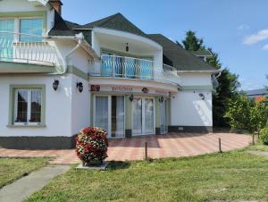 a white house with a porch and a balcony at Begónia Vendégház in Szigetszentmiklós