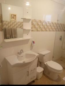 a white bathroom with a toilet and a sink at Apartamento en el residencial reparto los tres ojos in Ensanche Savica de Mendoza
