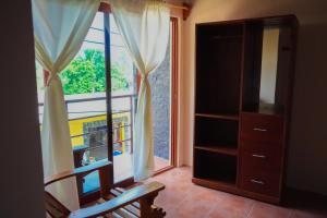 een kamer met een raam, een stoel en een boekenplank bij Posada El Mágico in Mazunte