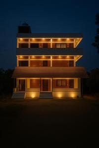 オーロヴィルにあるSrishti Guest Houseの夜にライトが点灯する大きな建物
